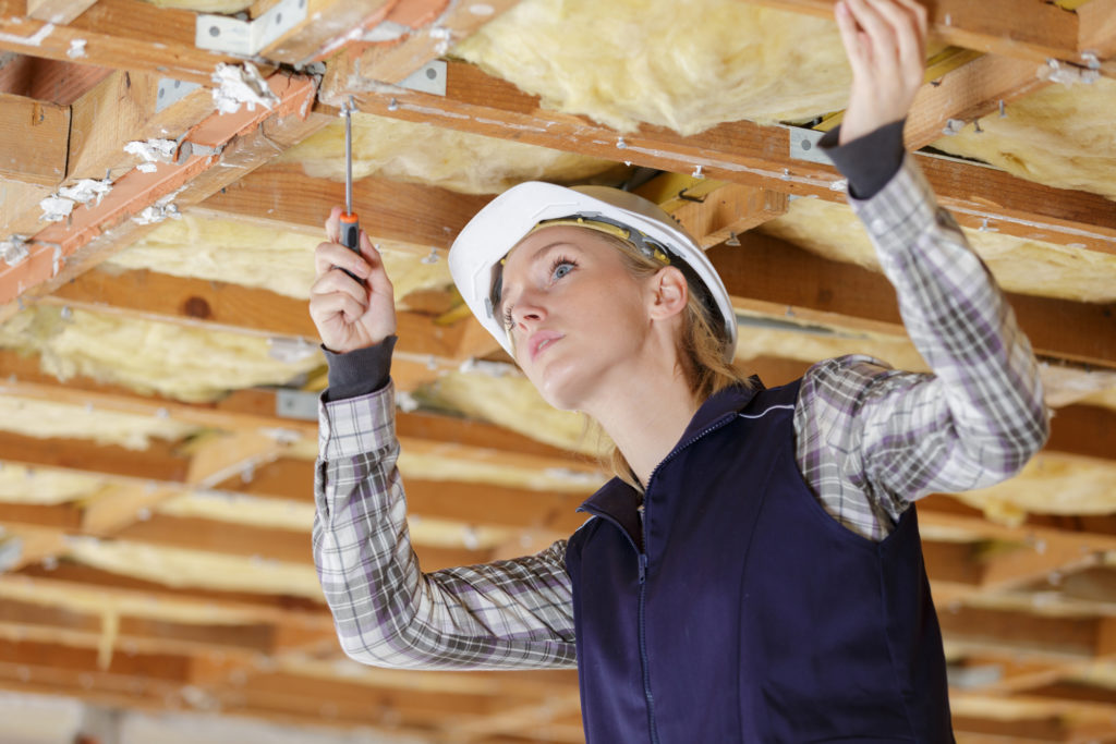 Woman installs insulation to save energy stop climate change save money.