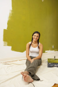 Woman painting her home green using eco friendly paint
