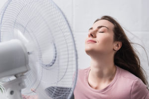 Energy-saving fan helps woman cool off.